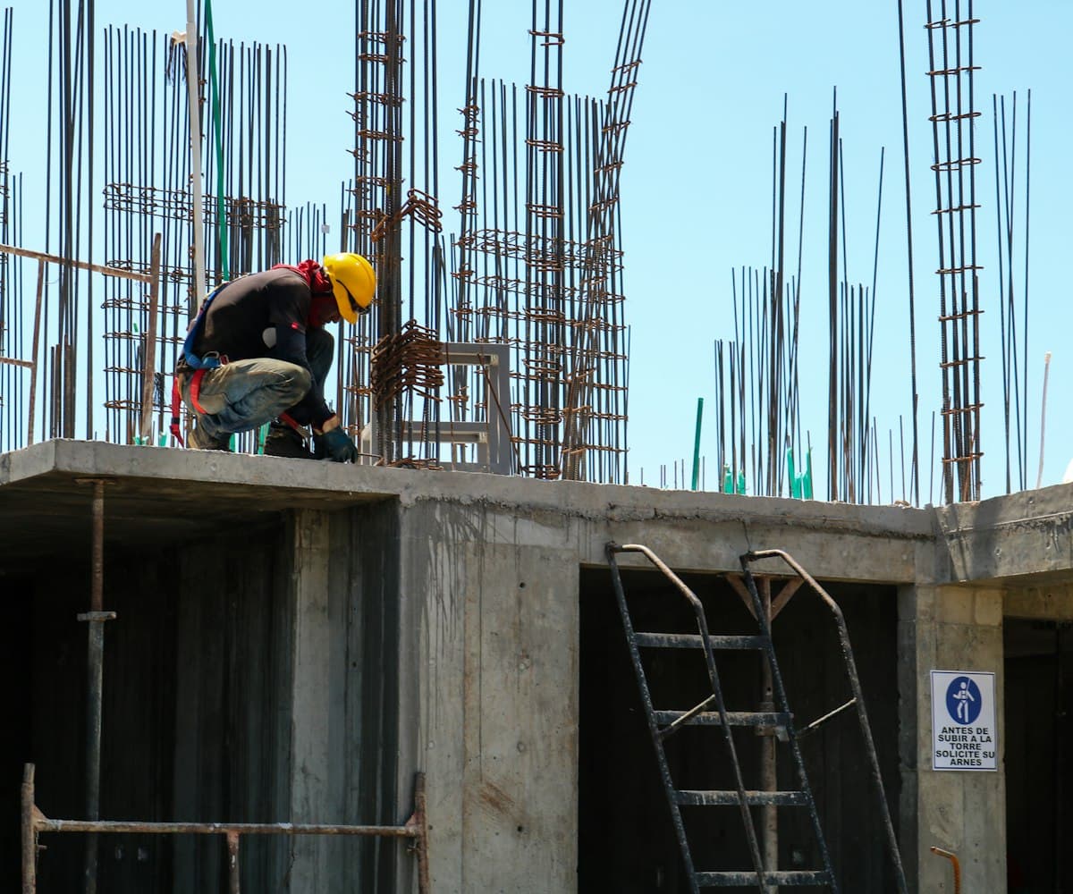 A concrete worker kneeling to finish a freshly poured surface